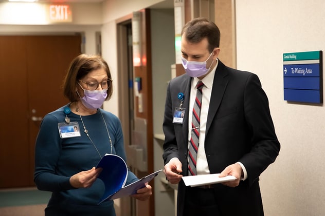 A surgeon confers with a care team member.